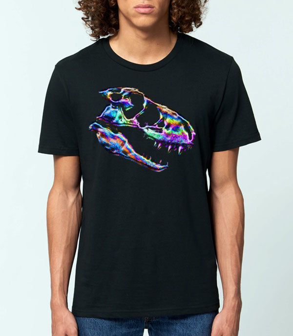 A man wearing a black crewneck t-shirt with a vibrant, multicolored oil spill inspired tyrannosaurus rex skull graphic on the chest, set against a plain light gray background.