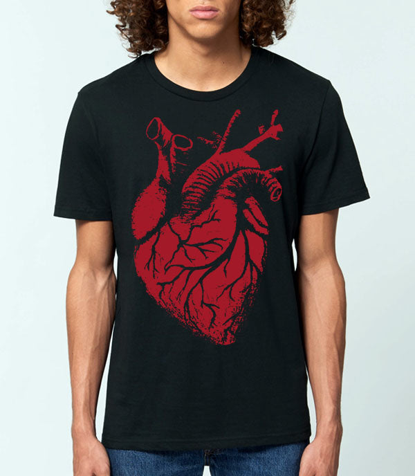 A man wearing a black short-sleeve crewneck t-shirt with a large red anatomical heart graphic on the front, paired with blue jeans, against a light gray background.